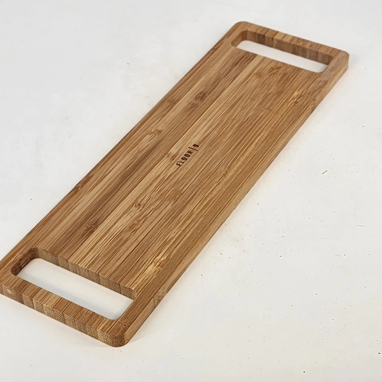 Bamboo cutting board with handles on a white surface