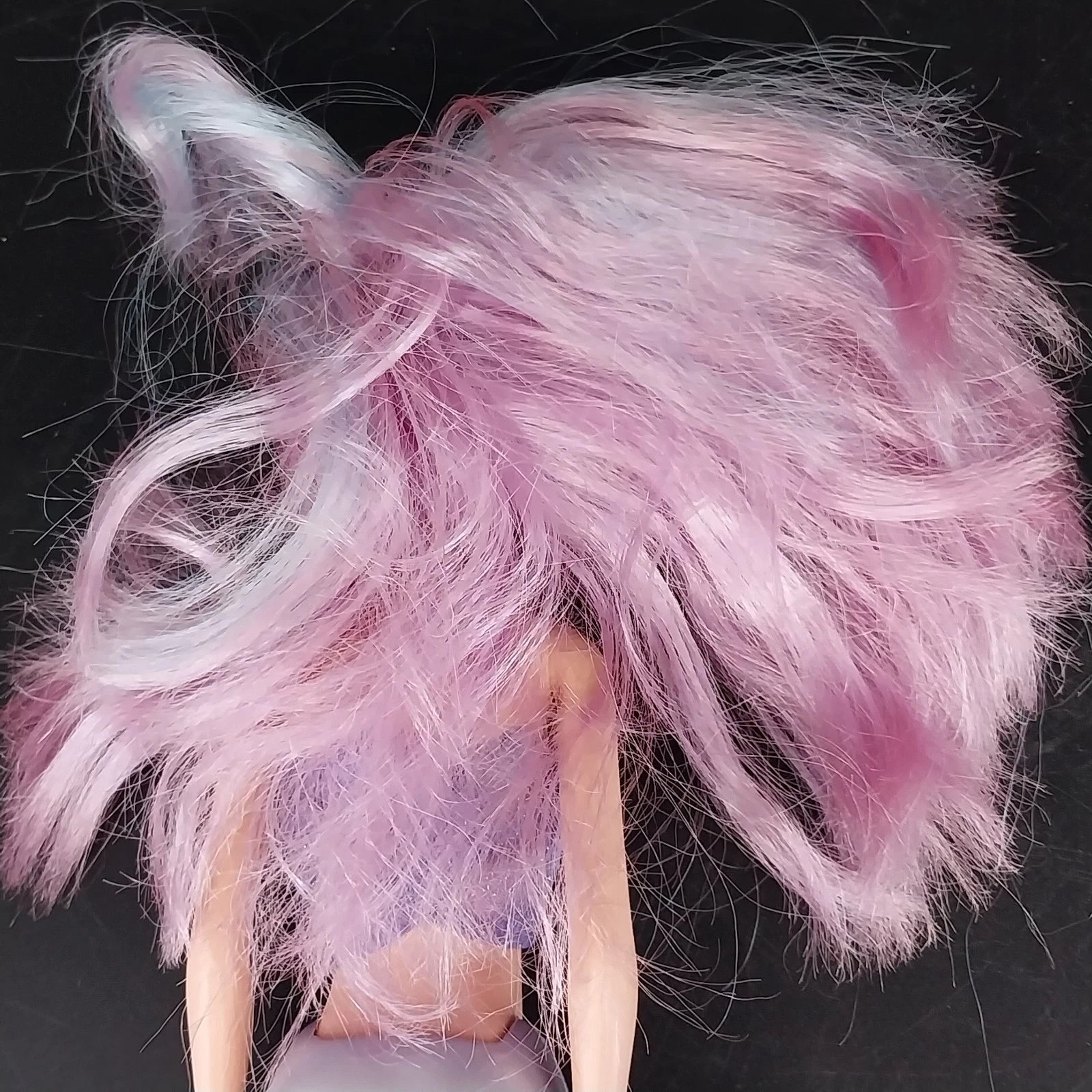 Close-up of a doll with pink and white hair against a black background