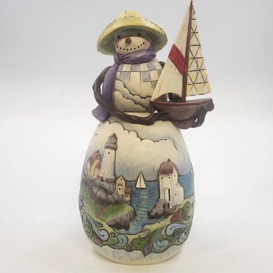 Jim Shore snowman figurine holding sailboat with coastal village scene