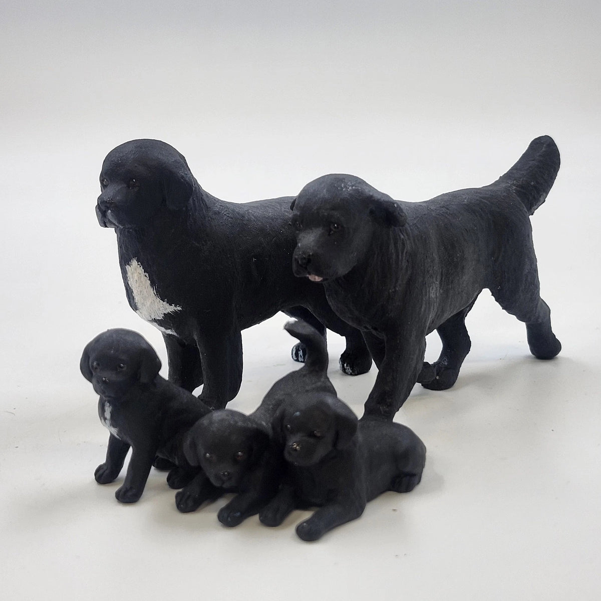 Set of five black Labrador dog figurines with two adult dogs and three puppies