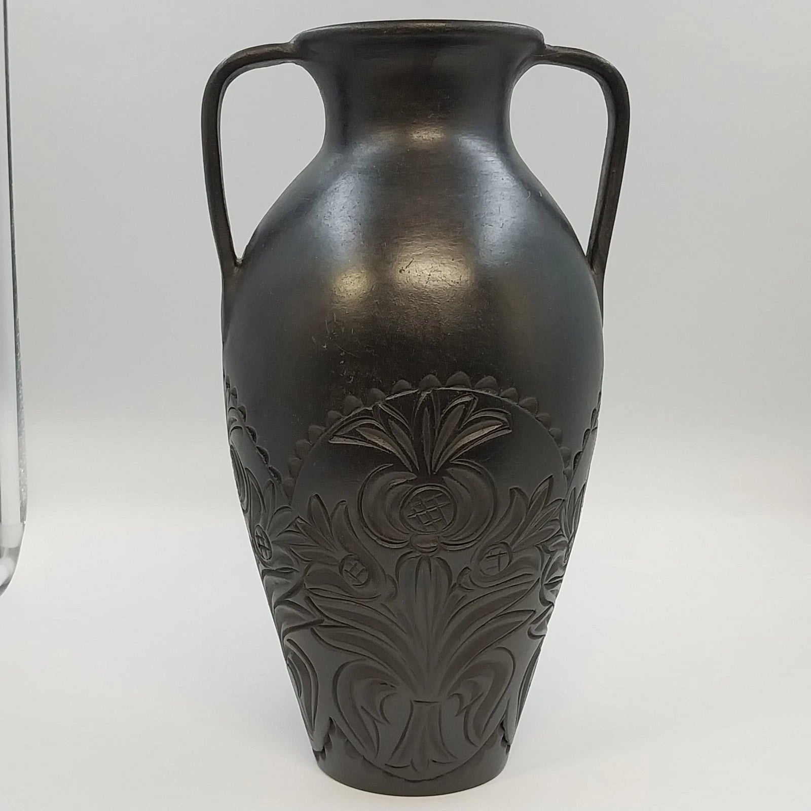 Black pottery vase with double handles and raised floral design