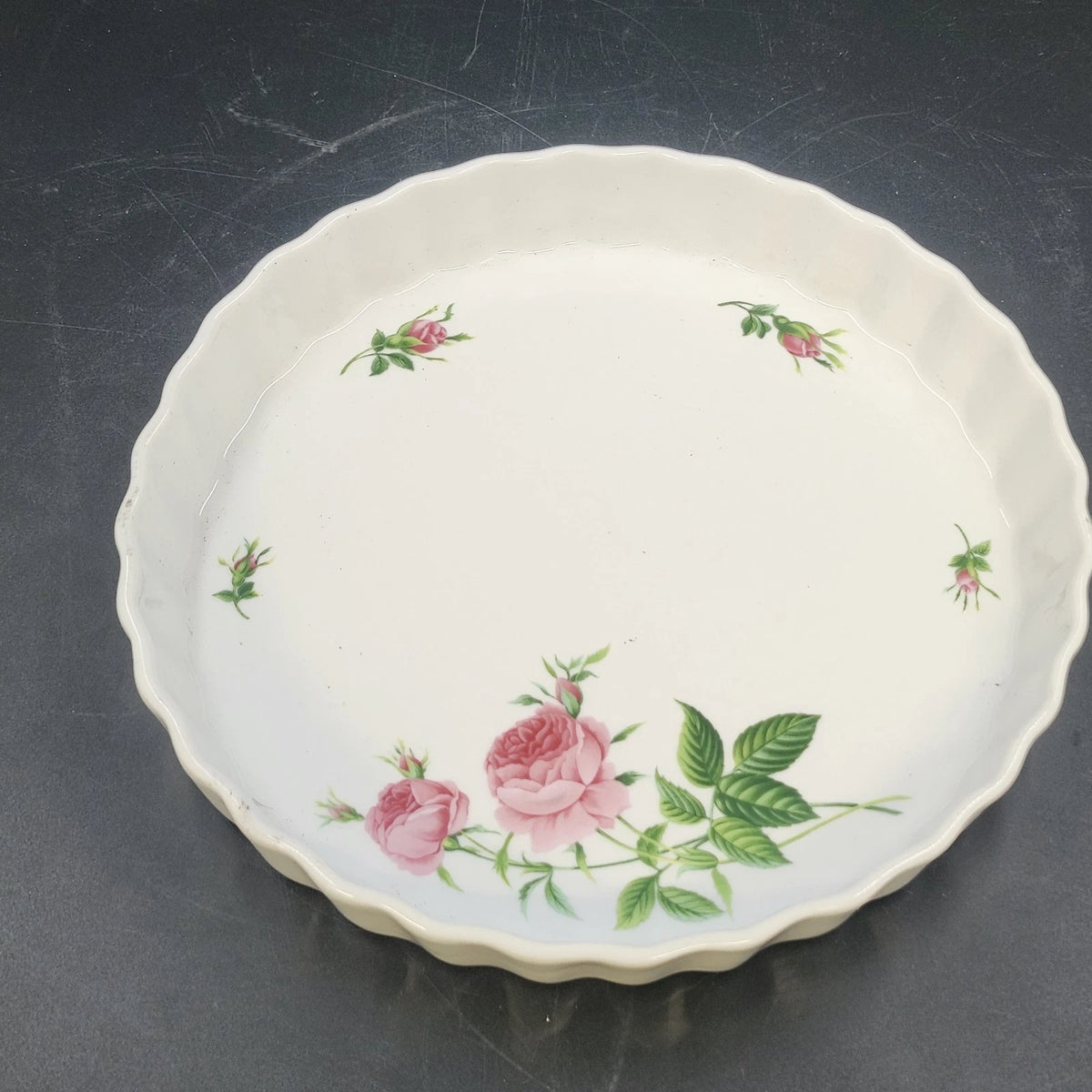 Christyneholm round porcelain baking dish with pink roses, green leaves, and scalloped edges.