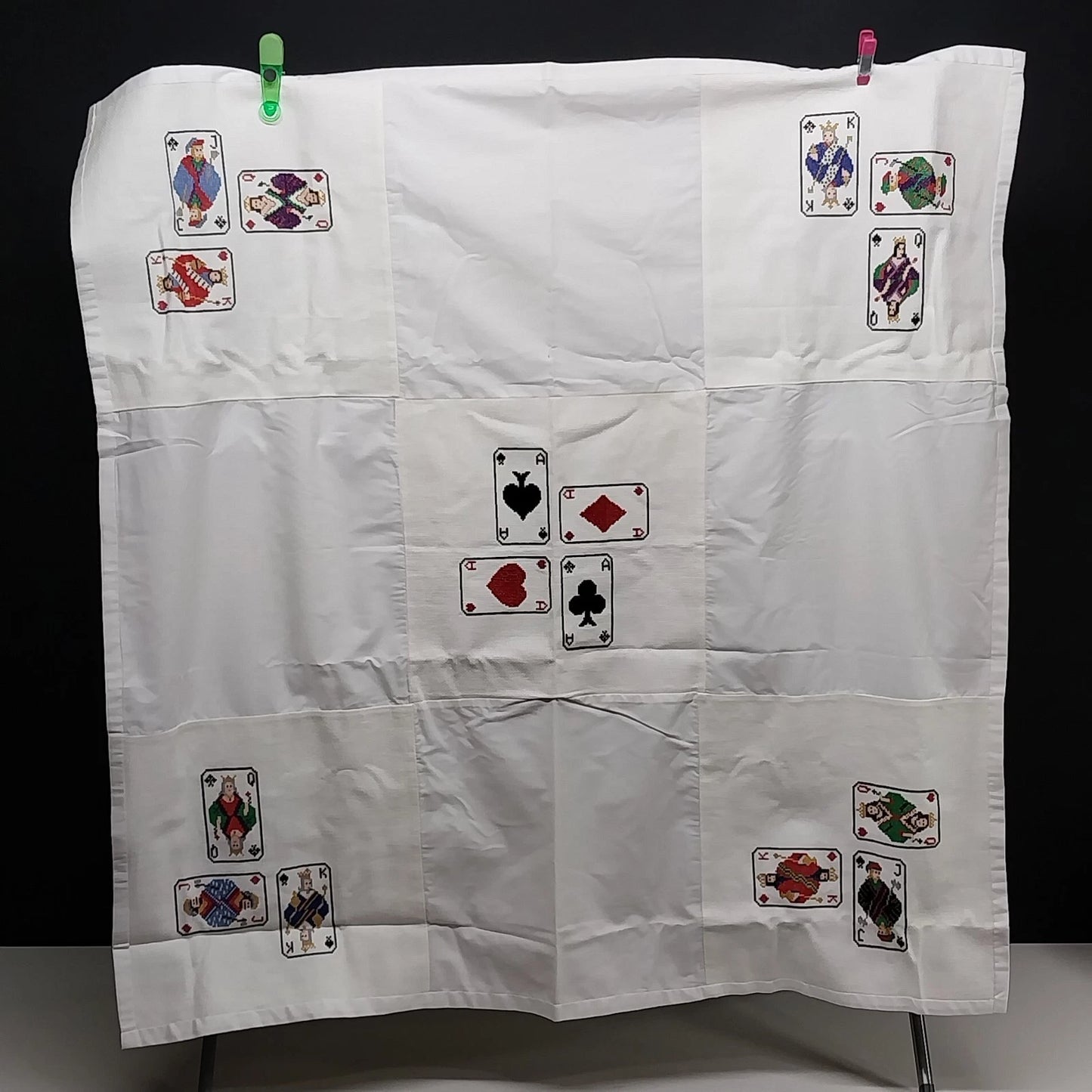 White embroidered card table cover with playing card designs