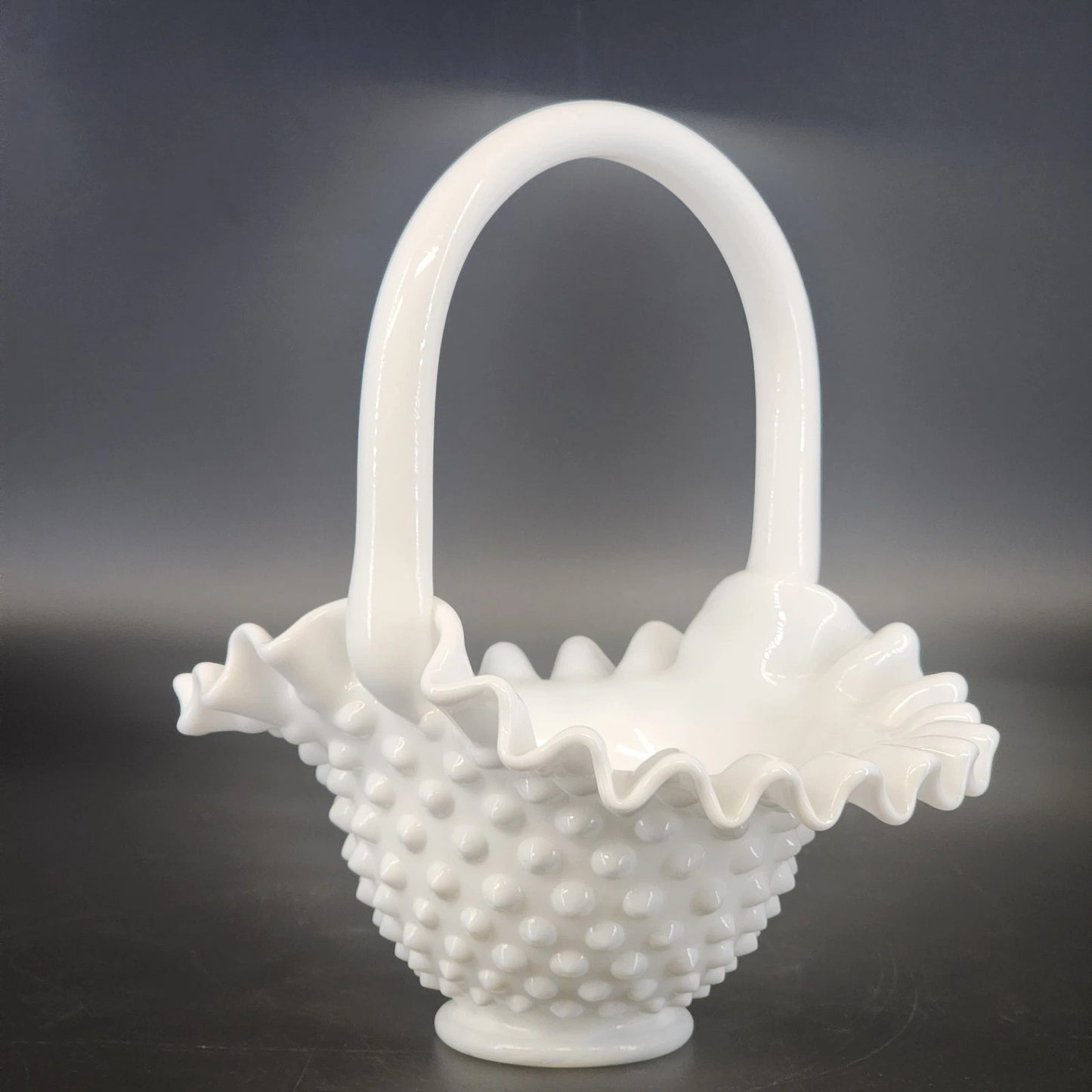 White glass basket with textured design on a dark background