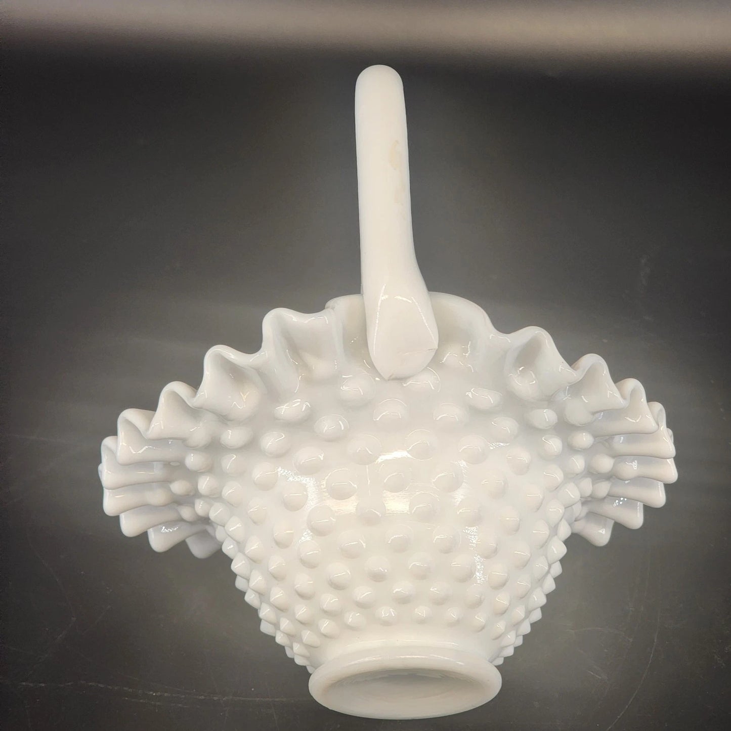 White textured vase with a handle on a dark background