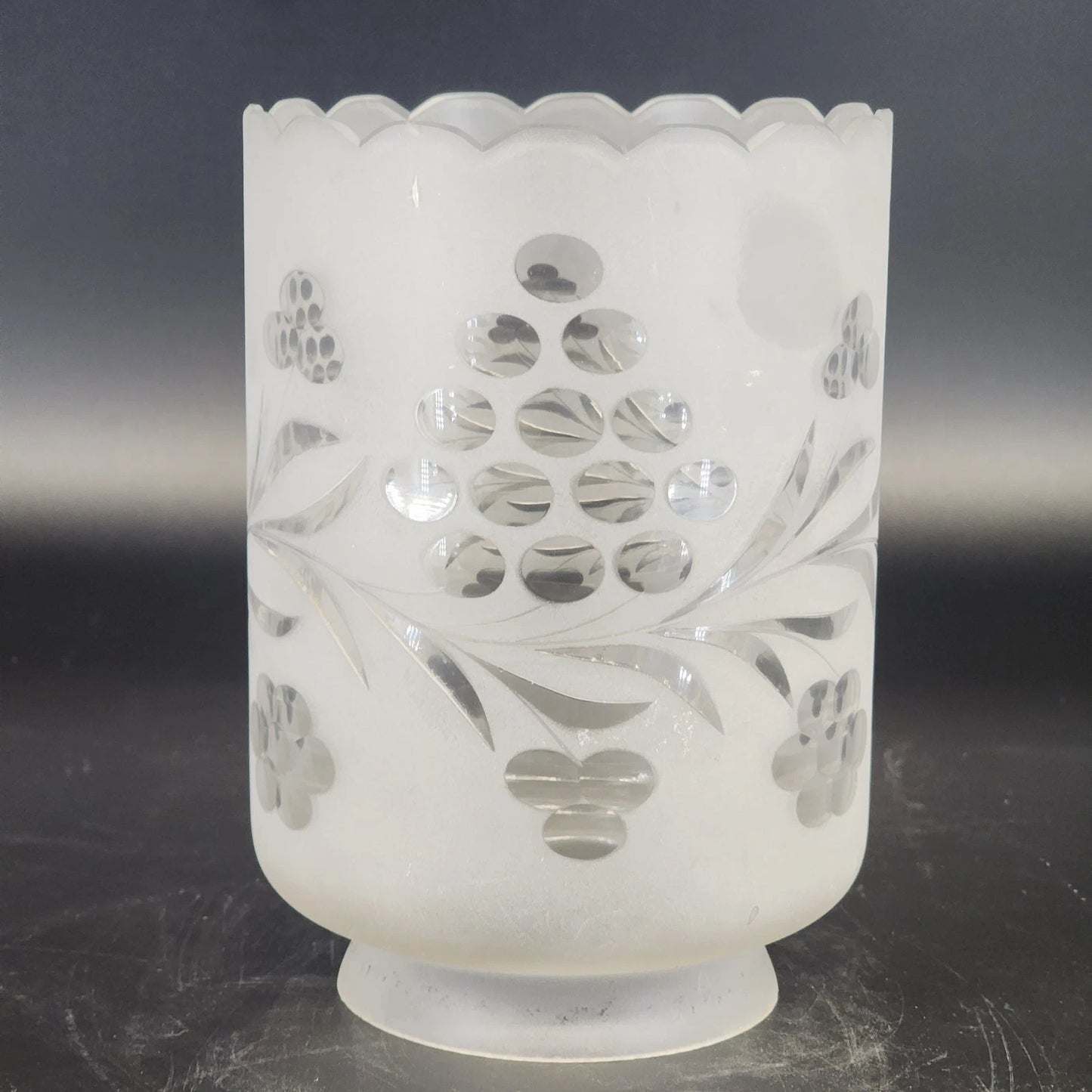 Decorative glass candle holder with floral cutout design on a dark background