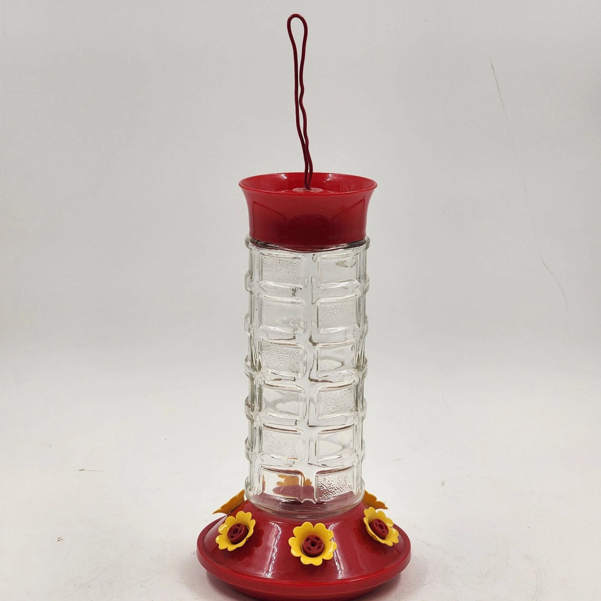 Clear glass hummingbird feeder with red base and six yellow flower ports