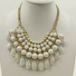 Gold tone bib necklace with white faceted round and teardrop beads