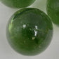 Clear round Jolen glass marble with shaded solid green coloring.
