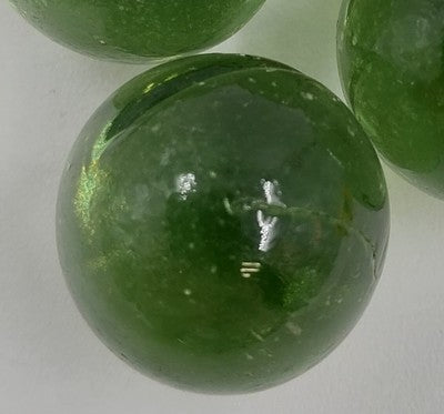 Clear round Jolen glass marble with shaded solid green coloring.