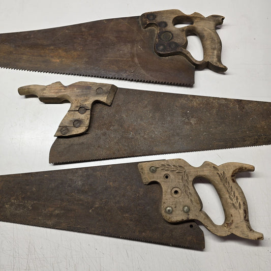 Lot of three old hand saws with wood handles, rusty steel blades, and heavy wear.