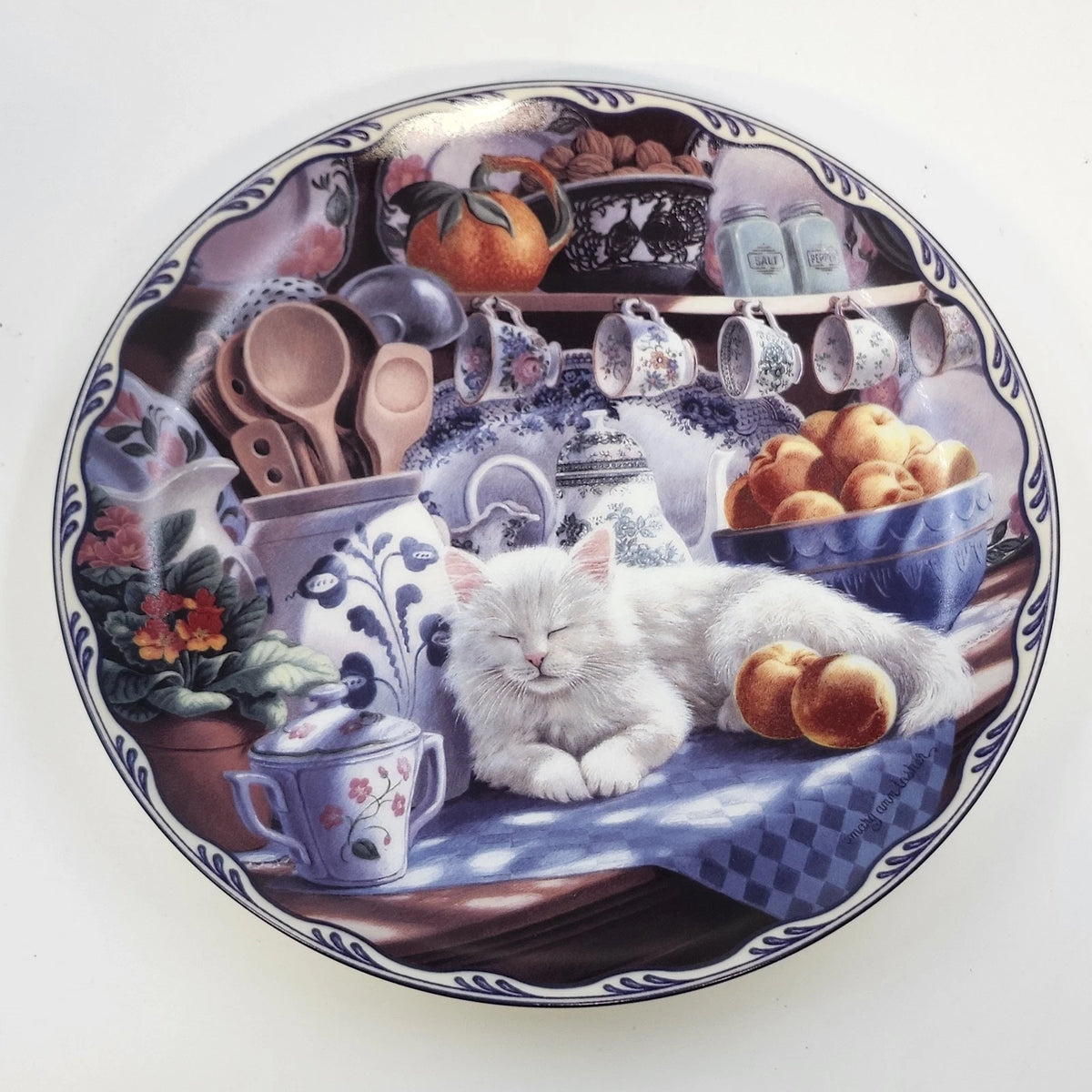 Mabel's Sunny Retreat collectible porcelain plate featuring a sleeping white cat on a blue checkered tablecloth in a country kitchen.