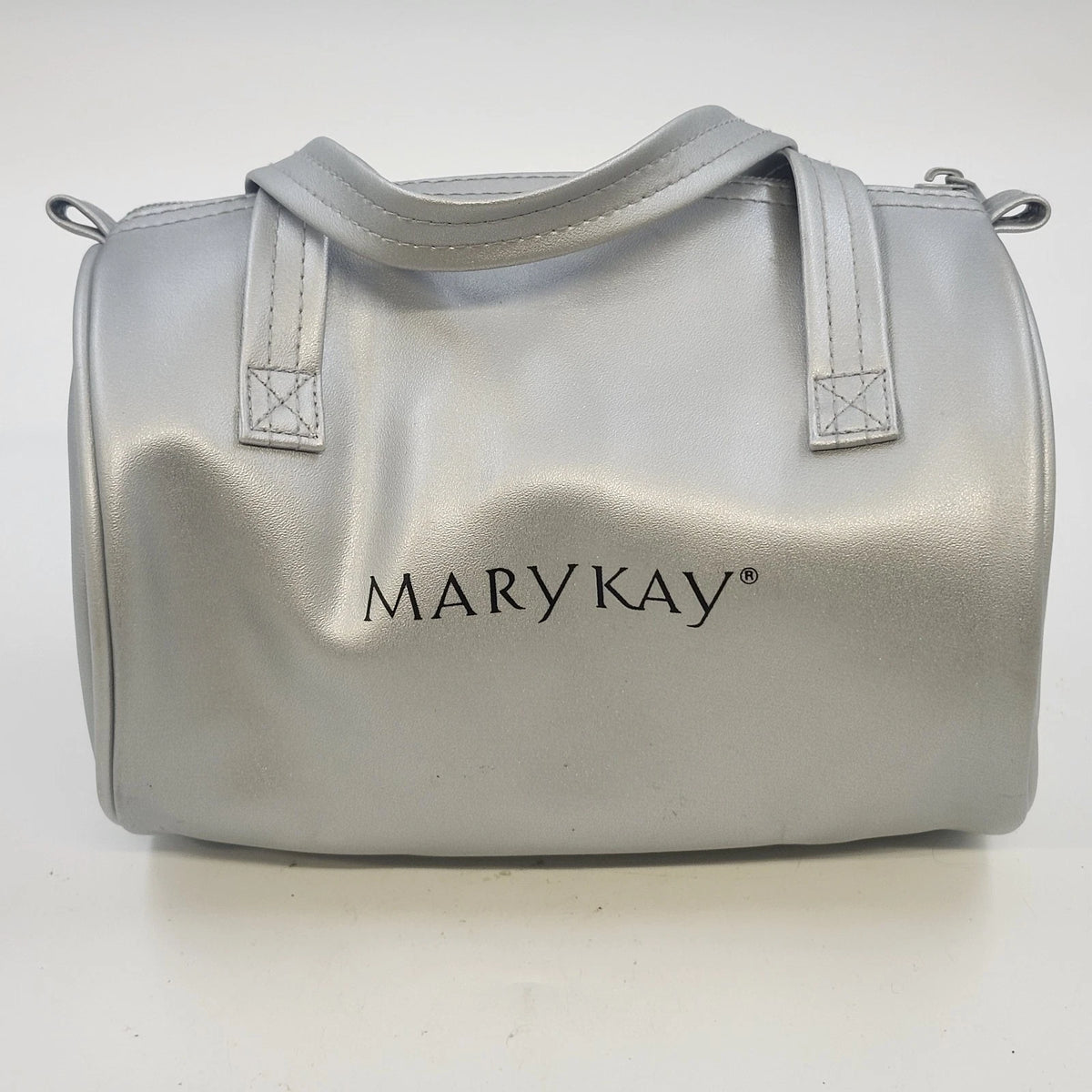 Mary Kay silver metallic barrel cosmetic bag with dual handles and zipper closure.