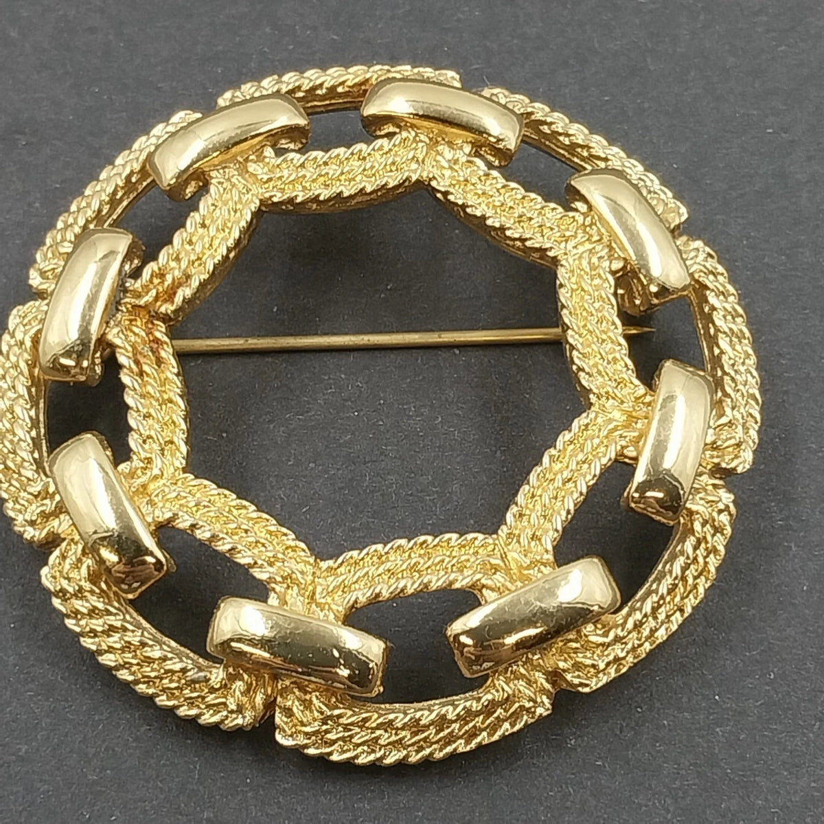 Signed Monet gold tone circular brooch with interwoven rope texture and open center