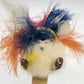Handmade folk art figure with colorful feathers and rustic wood base