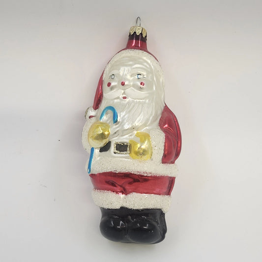 Hand-painted blown glass Santa Claus Christmas ornament in a red suit with white glitter trim, black boots, and candy cane