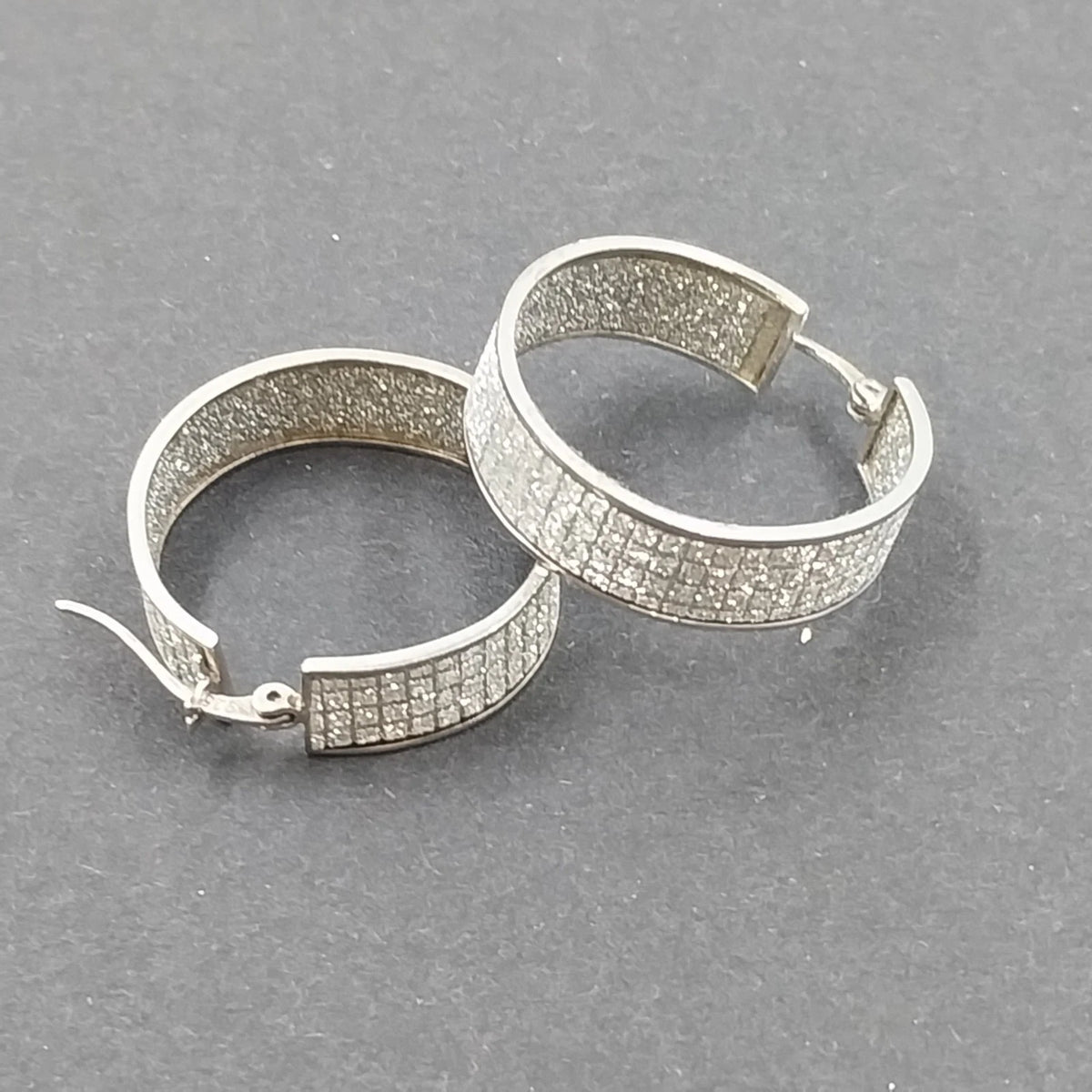 Silver tone wide pave hoop earrings with white rhinestones
