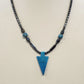 Black beaded necklace with blue arrowhead pendant and metallic accents