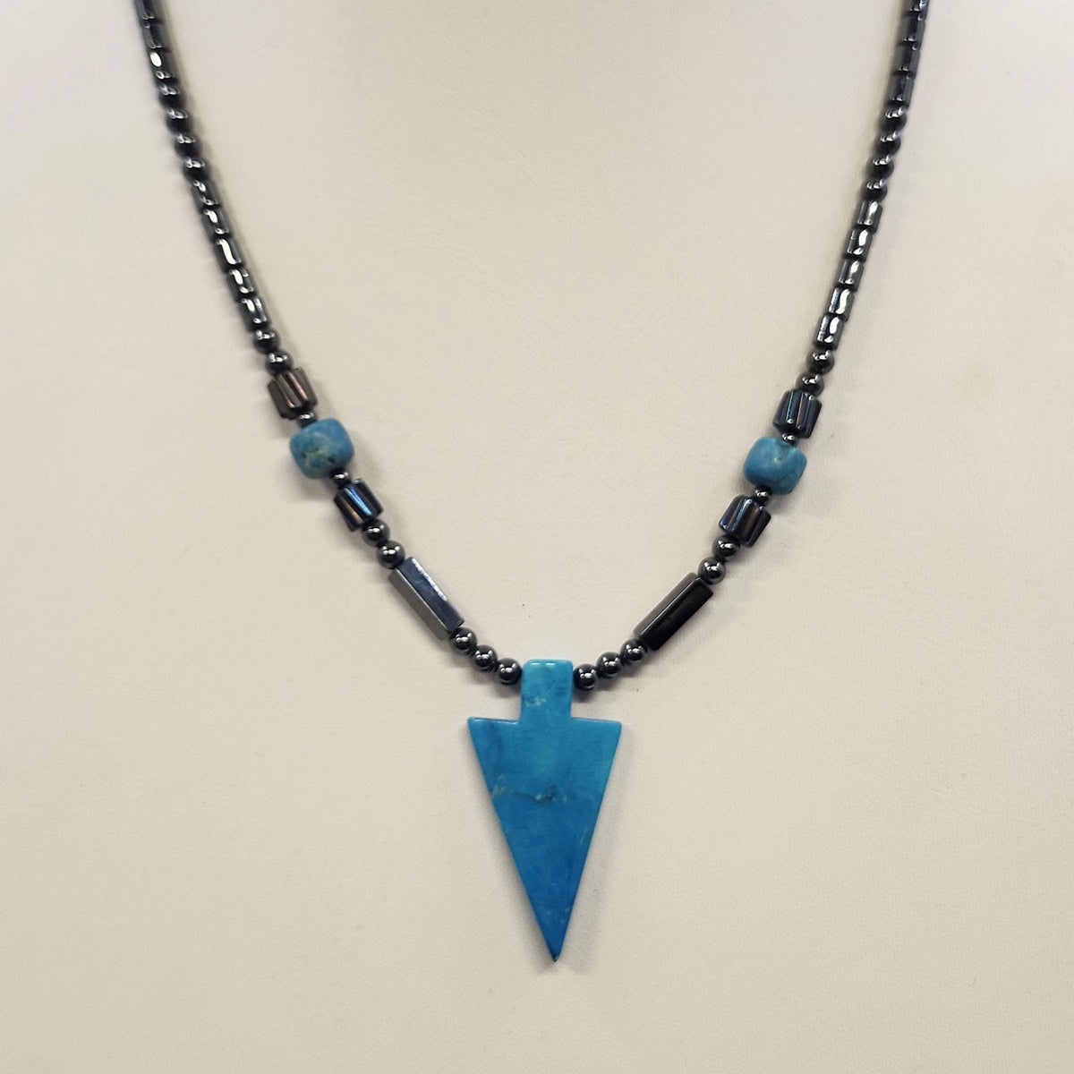 Black beaded necklace with blue arrowhead pendant and metallic accents
