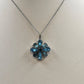 Silver-tone necklace with a flower pendant featuring faceted blue teardrop stones and a dark center.