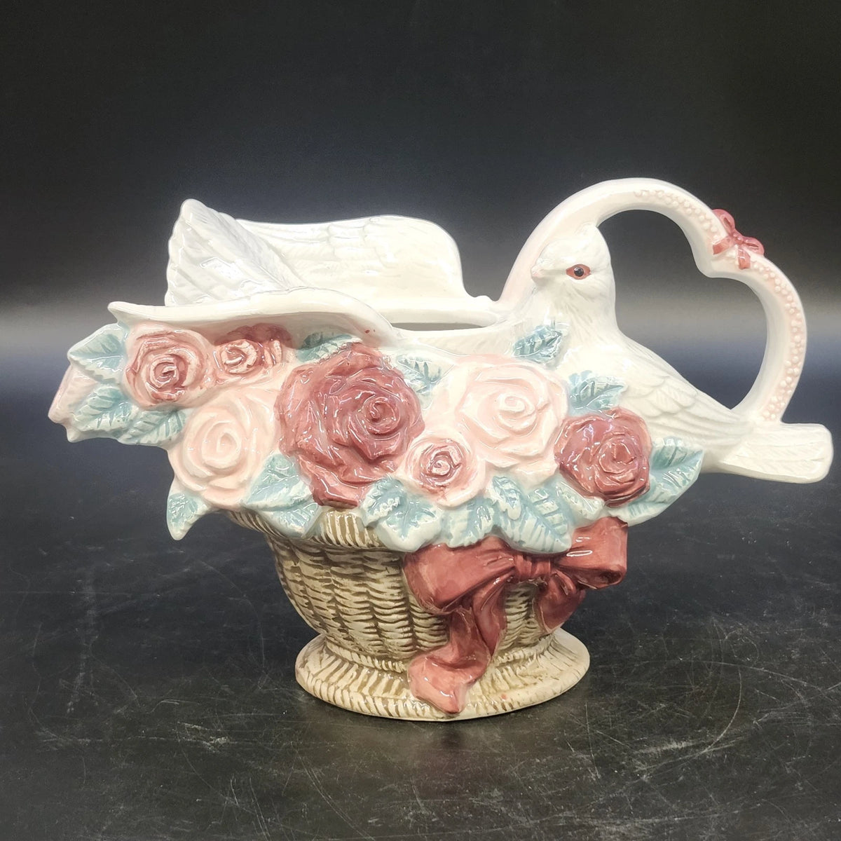 Vintage ceramic dove pitcher vase with pink roses, heart-shaped handle, and woven basket base
