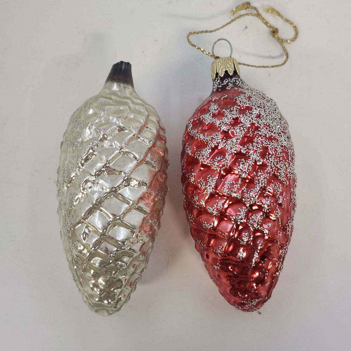 Pair of vintage glass pinecone Christmas ornaments in metallic red and silver.