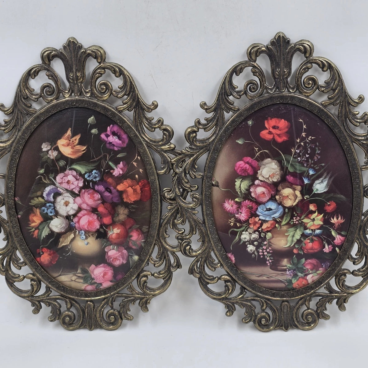 Pair of oval floral prints with ornate gold frames and convex glass