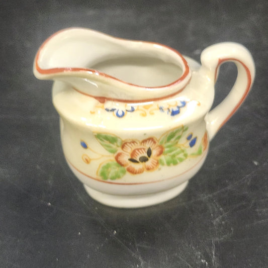 Vintage Japan porcelain creamer pitcher with hand-painted floral design and orange trim