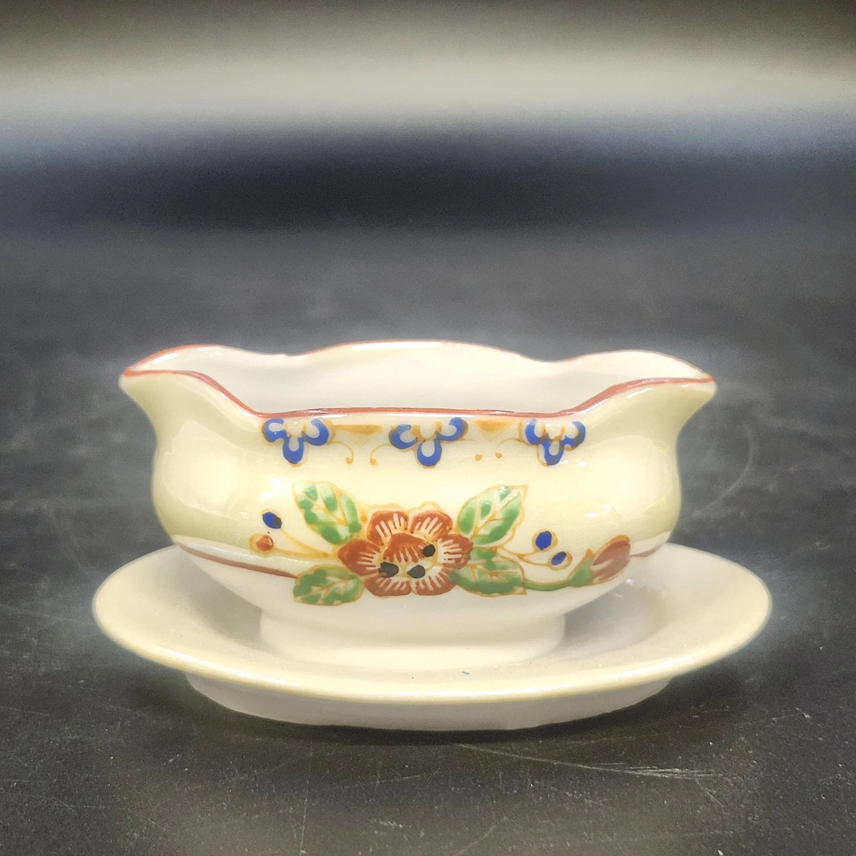 Vintage Japan porcelain gravy bowl with attached underplate and floral design