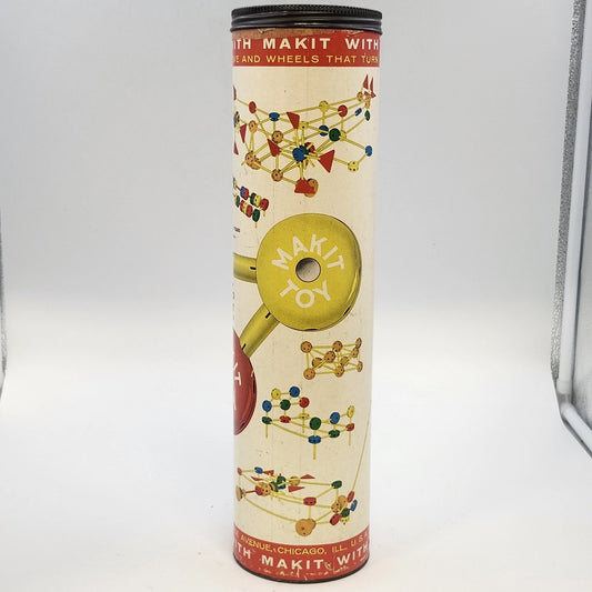 Vintage Makit wooden construction toy set with colorful cylindrical storage container, natural wood dowel rods, drilled hubs, and red, blue, and yellow wheels and components.