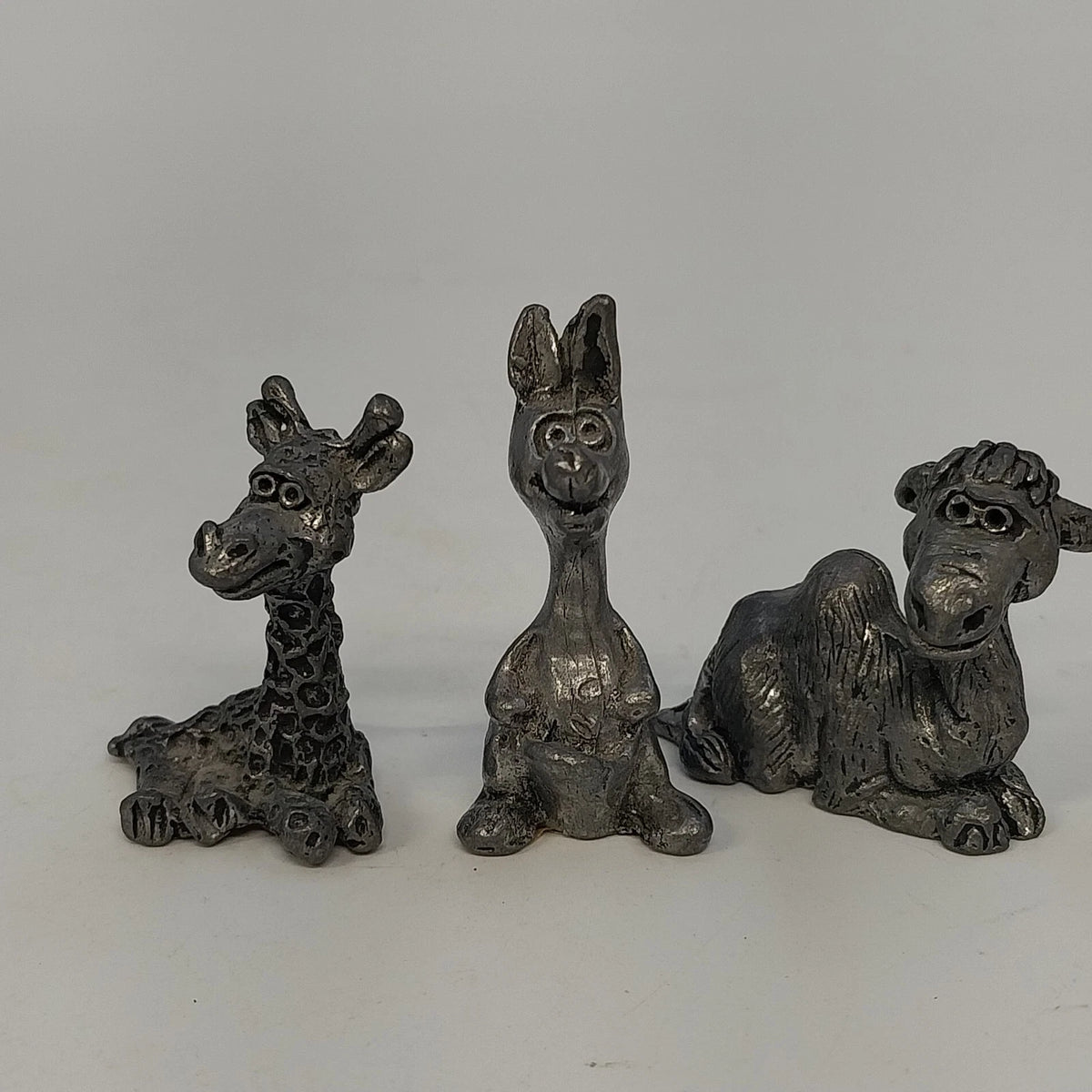Three vintage pewter giraffe kangaroo and monkey figurines