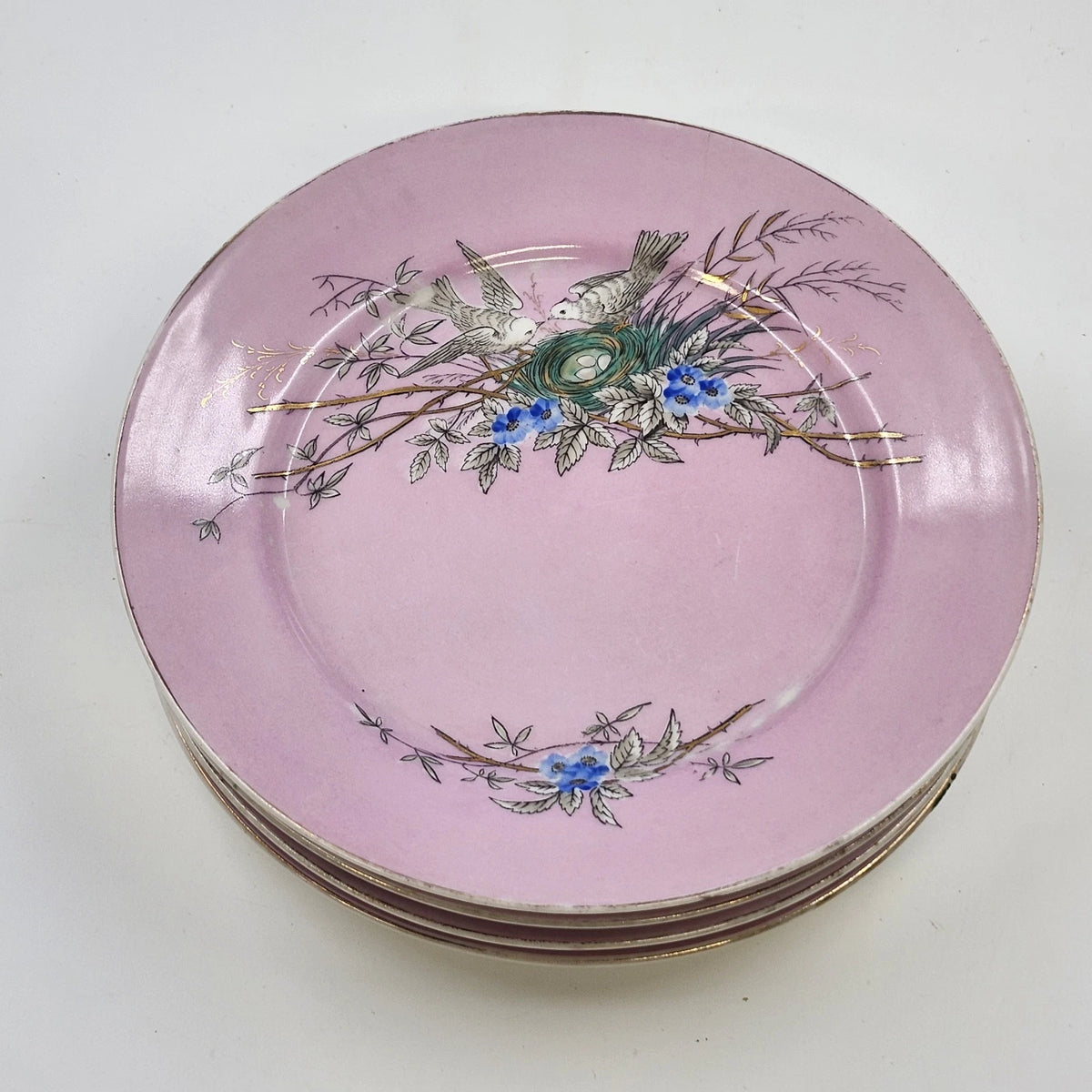 Set of four vintage pink porcelain plates with bird nest and blue flowers