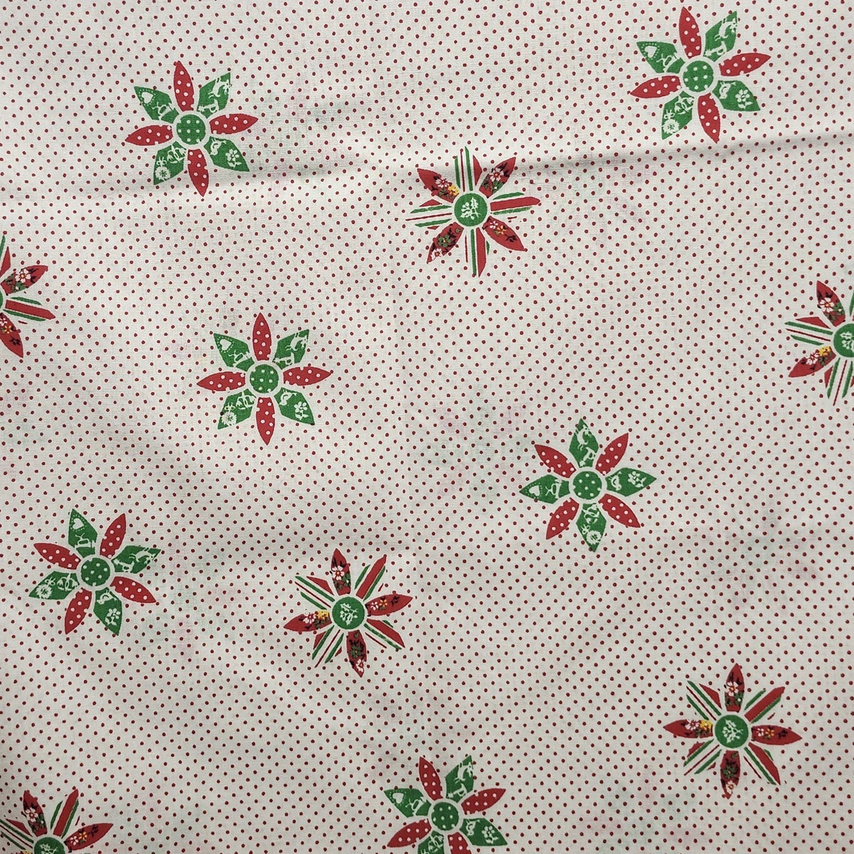 Vintage Christmas tablecloth with red polka dots, green and red poinsettia motifs, and red edging.