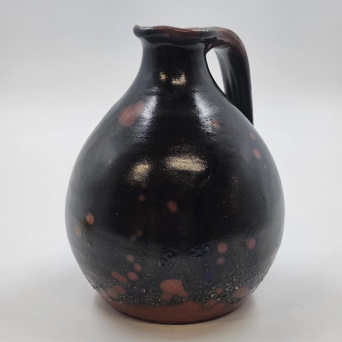 Small redware pottery pitcher with dark mottled brown glaze
