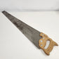 Vintage Stanley 26-inch crosscut hand saw with aged steel blade, shaped wooden handle with decorative incised details, Stanley medallion, and hanging hole.