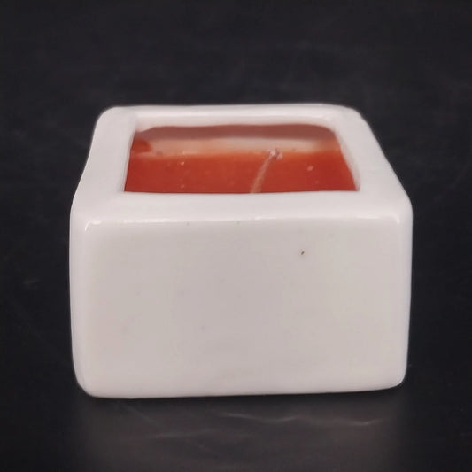 White ceramic square container candle with recessed red wax and single wick