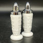 Pair of white milk glass salt and pepper shakers with raised grape and vine designs and silver-tone metal tops.