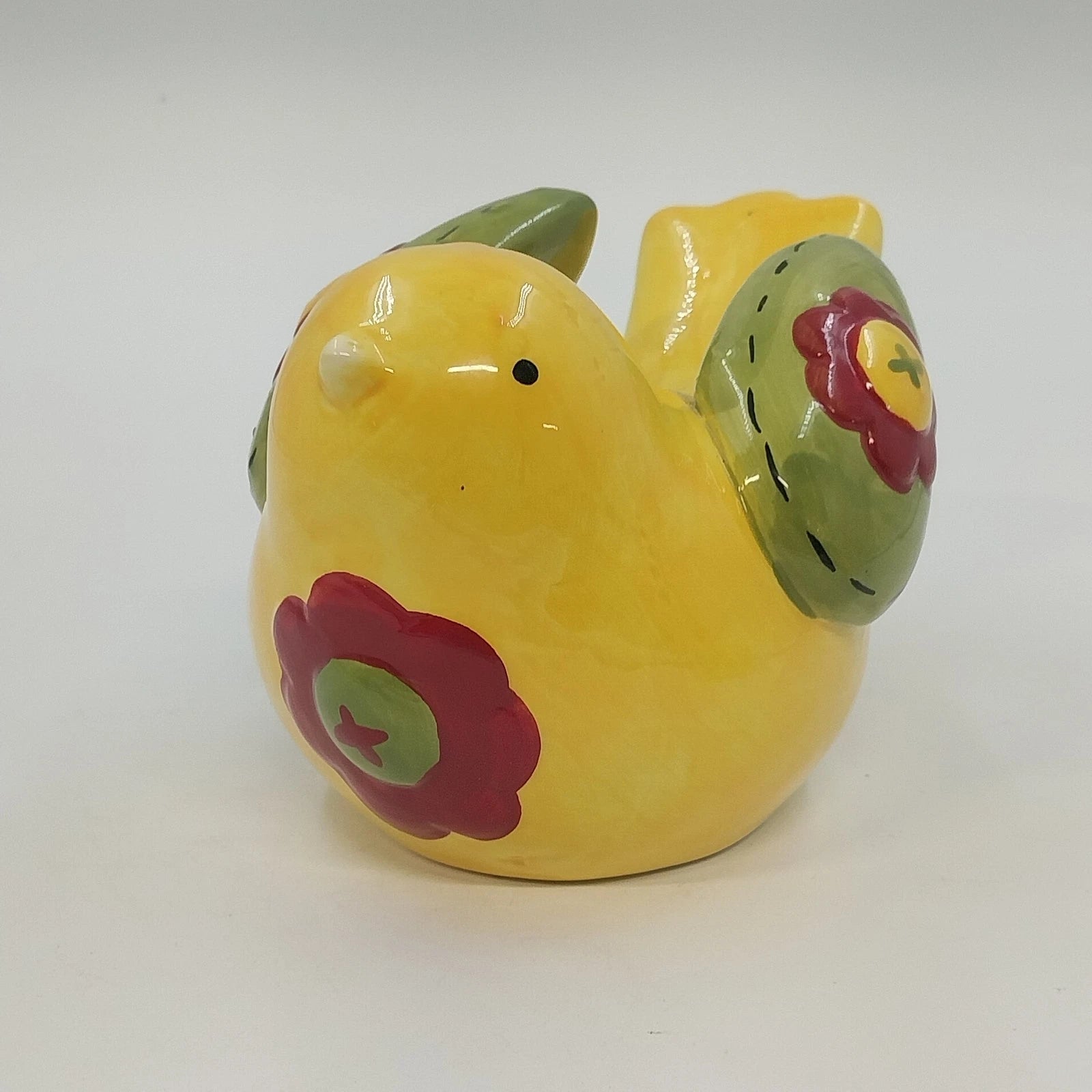 Yellow ceramic bird figurine with green wings and red floral accents